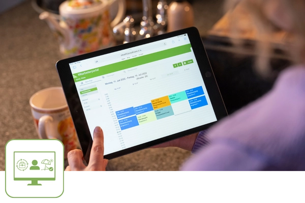 Ein Tablet zeigt einen Terminkalender aus JCC-Personalplanung. Links unten ist ein grünes Icon mit einem Monitor zu sehen.