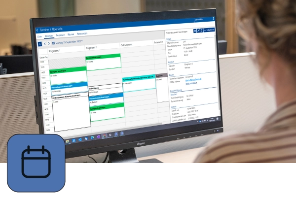 Sachbearbeiterin schaut auf einen Monitor, worauf ein Kalender von JCC-Terminvereinbarung zu sehen. Links unten ist das blaue Icon dieser Anwendung abgebildet.